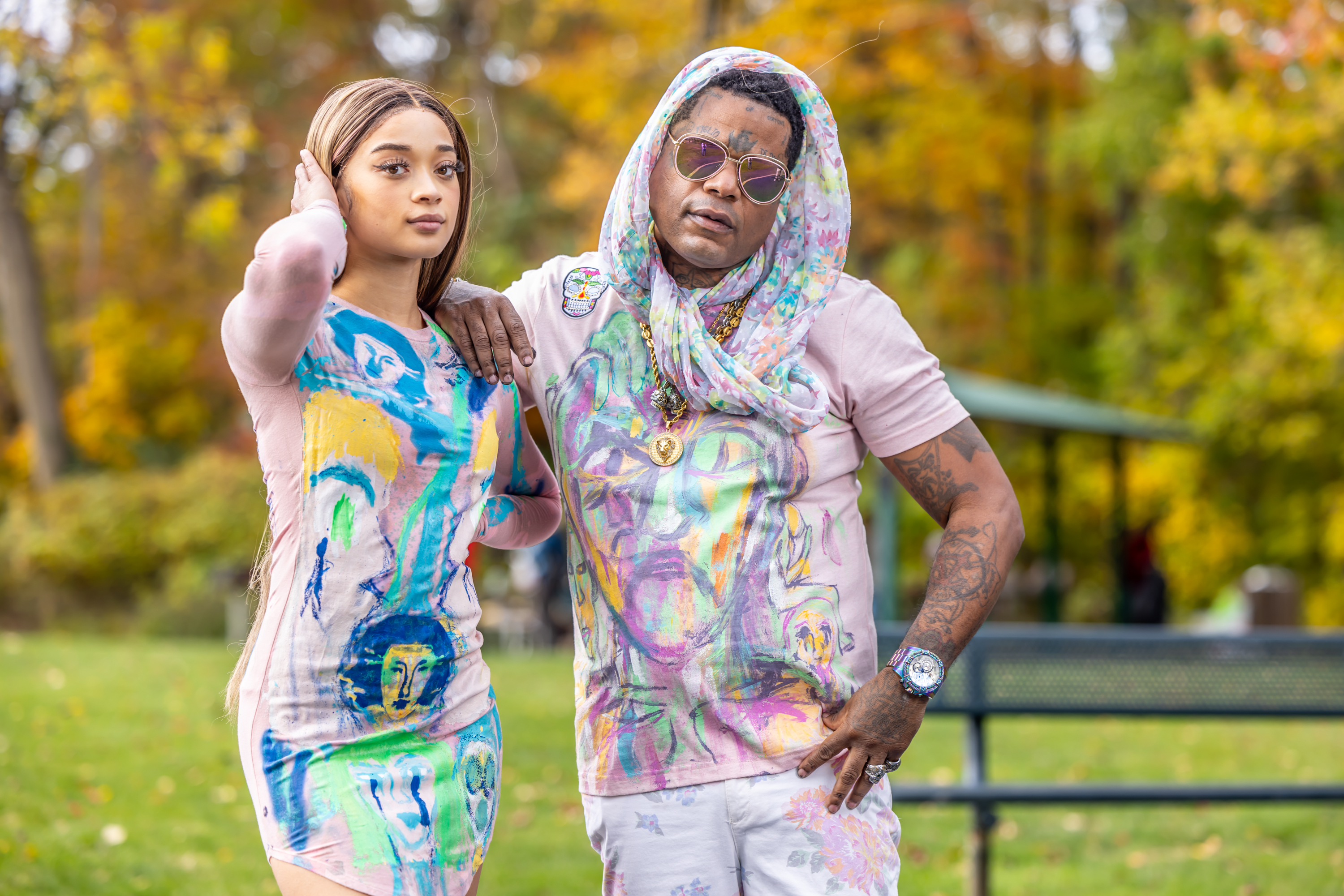 Franco and model in matching hand-painted pink outfits with colorful face artwork at the park