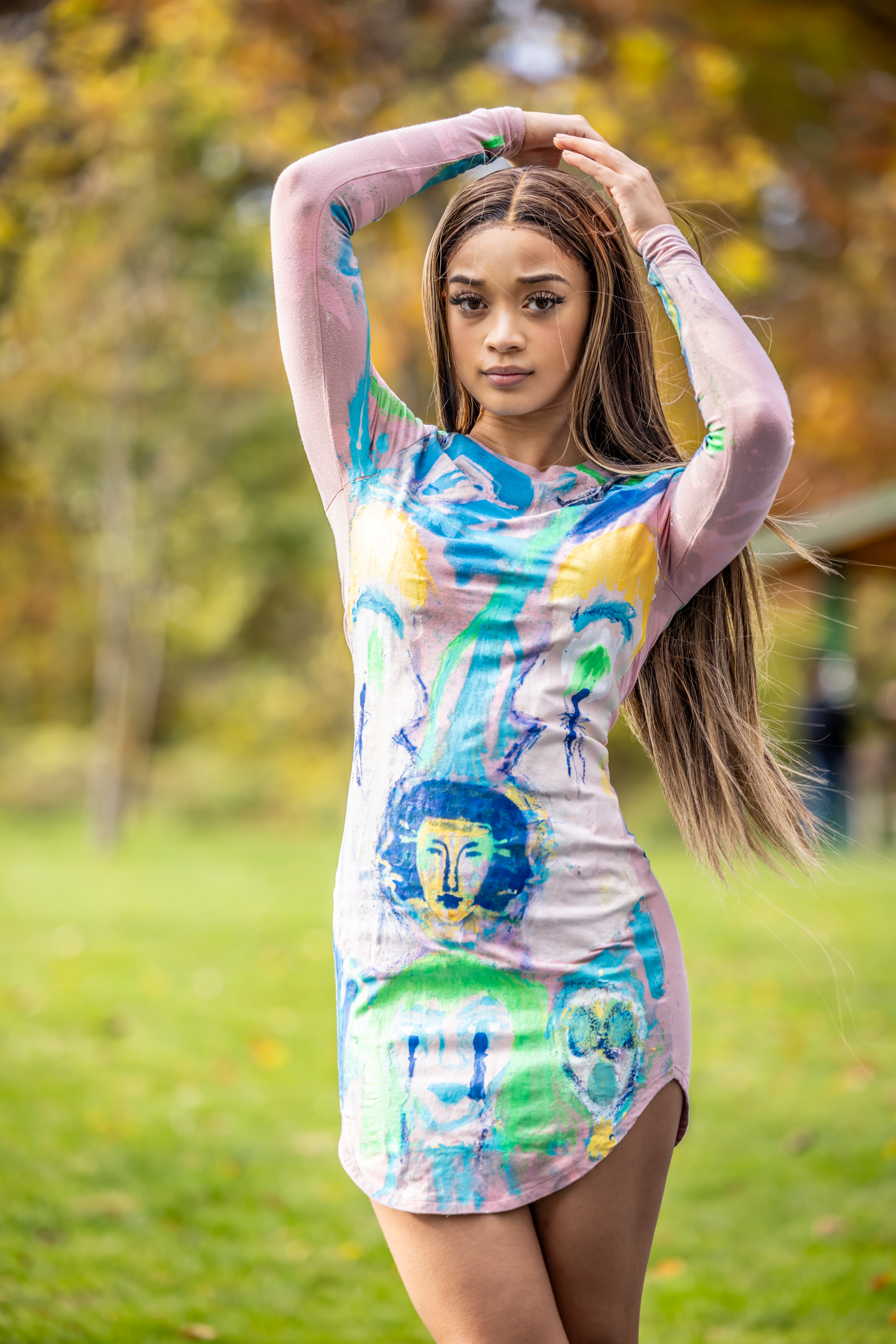 Model posing in hand-painted blue and green long-sleeve dress with face artwork