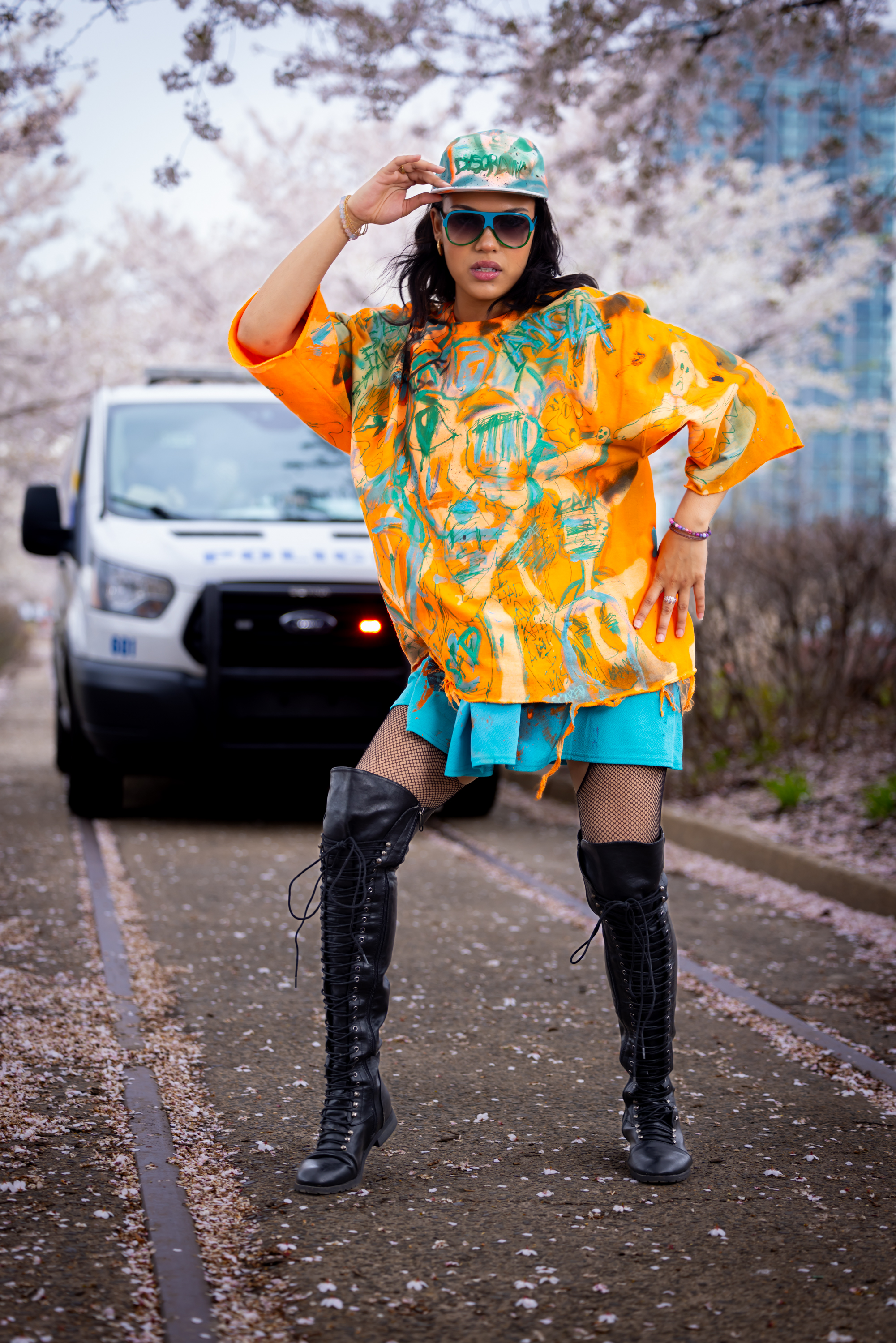 Model in an orange and teal hand-painted DiSoRdInE tee and cap